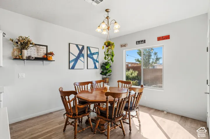 Wood-finish flooring, single window, white walls, and a multi-light chandelier