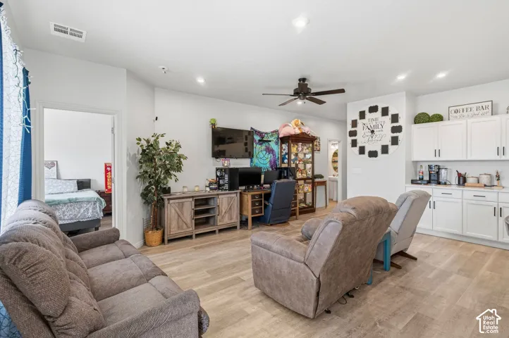Recessed lighting, wood-finish flooring, white cabinetry with dark hardware, and a ceiling fan