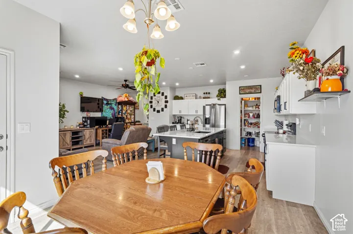 Wood-finish flooring, recessed lighting, white cabinetry, stainless steel refrigerator, and a kitchen island with seating