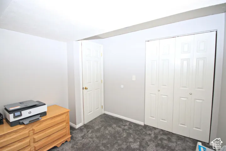 Textured ceiling, light gray wall paint, paneled interior door, bi-fold closet doors, and gray carpet flooring