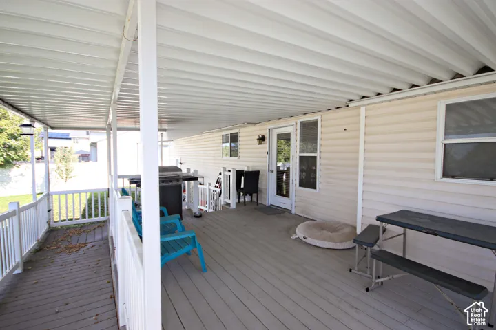 Covered deck that is wheelchair accessible with a corrugated roof, wood-finish decking, and white railing.