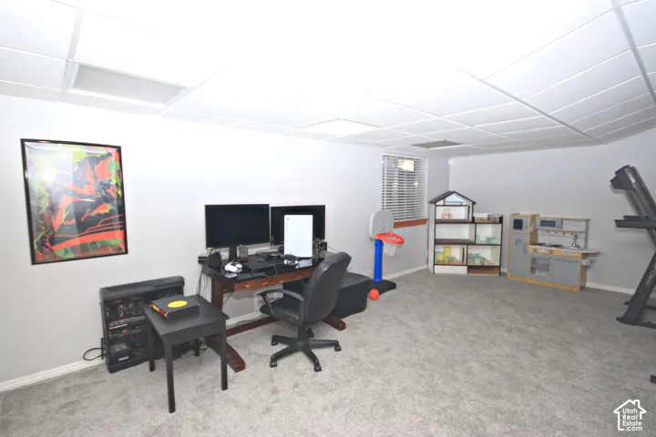 Recessed lighting panels, light gray wall paint, gray carpet flooring, and a single window with blinds
