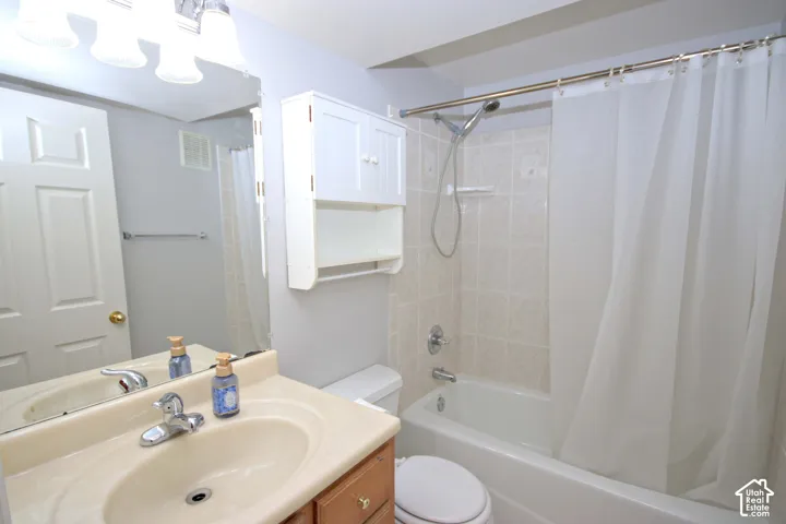 Bathroom featuring a single-sink vanity with wood-finish cabinetry, a built-in medicine cabinet, and a tiled shower-tub combination