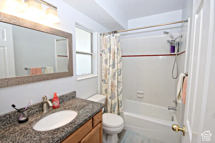 Ensuite bathroom featuring a granite-finish vanity, undermount sink, and a combination shower and tub with white tile surround