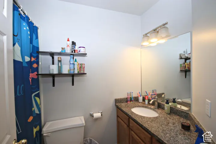 Bathroom featuring a vanity with an integrated sink, granite-style countertop, and a wall-mounted light fixture
