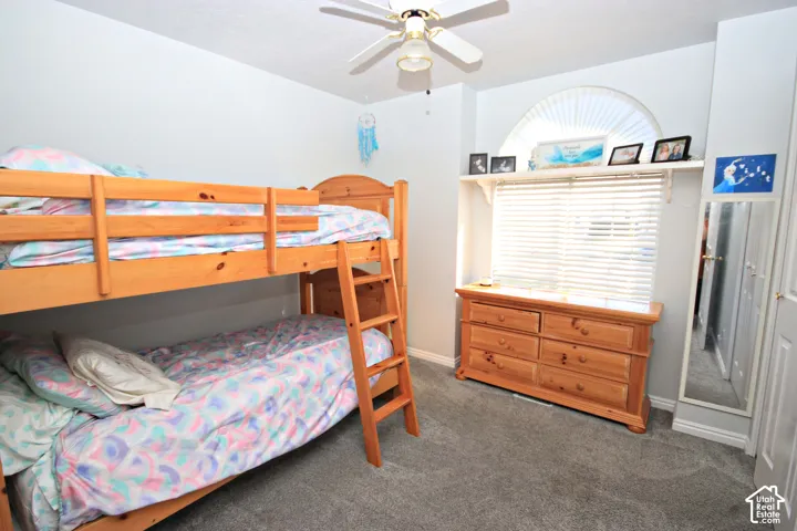 Carpeted flooring, ceiling fan, and arched window with blinds