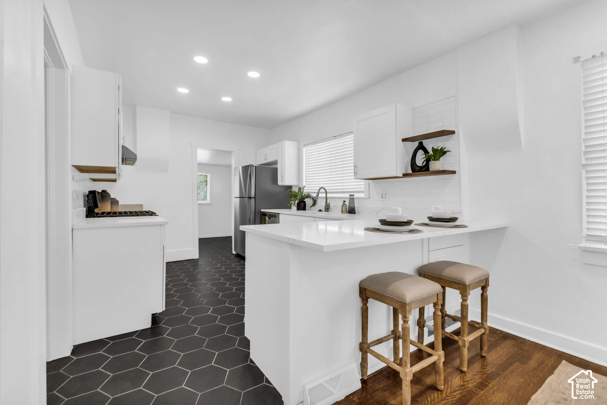 White cabinetry, hexagon tile flooring, stainless steel refrigerator, white subway tile backsplash, and recessed lighting