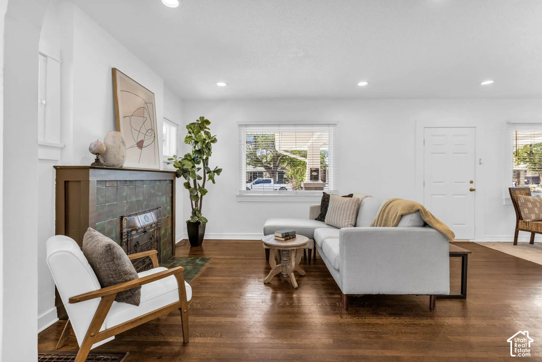 Hardwood flooring throughout, recessed lighting, prominent fireplace with tile surround, white trim, and multiple windows