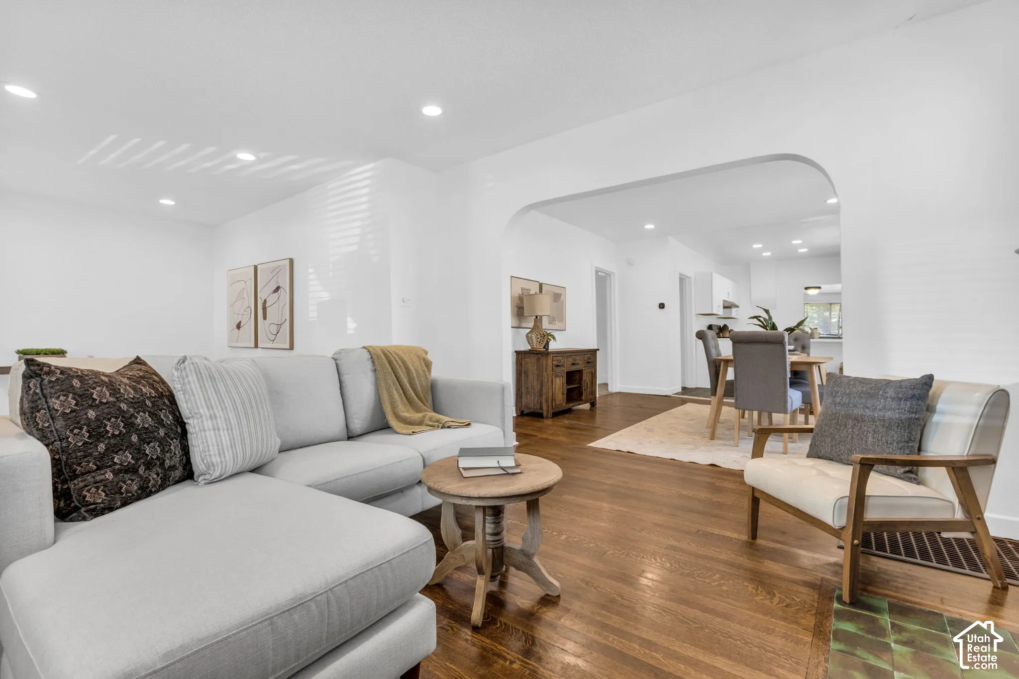 Rich wood-finish flooring throughout, recessed ceiling lighting, and a wide arched entryway