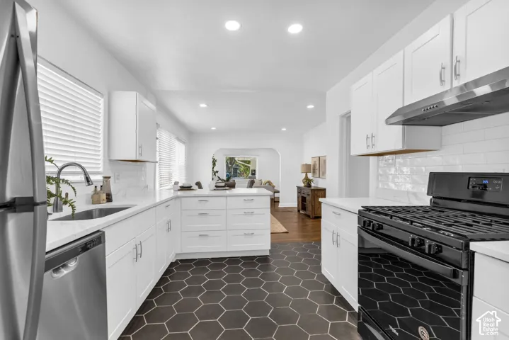 White cabinetry with brushed nickel hardware, white subway tile backsplash, white countertops, stainless steel appliances, and hexagon tile flooring