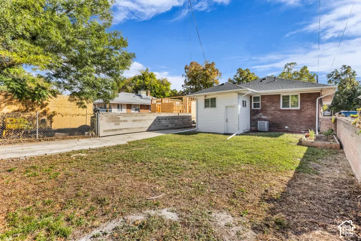 Brick exterior residence with a white siding addition, concrete block retaining wall, and an expansive lawn area