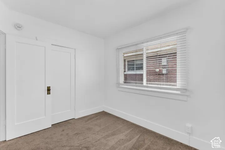 Neutral-toned carpeting, white walls, and a window with blinds