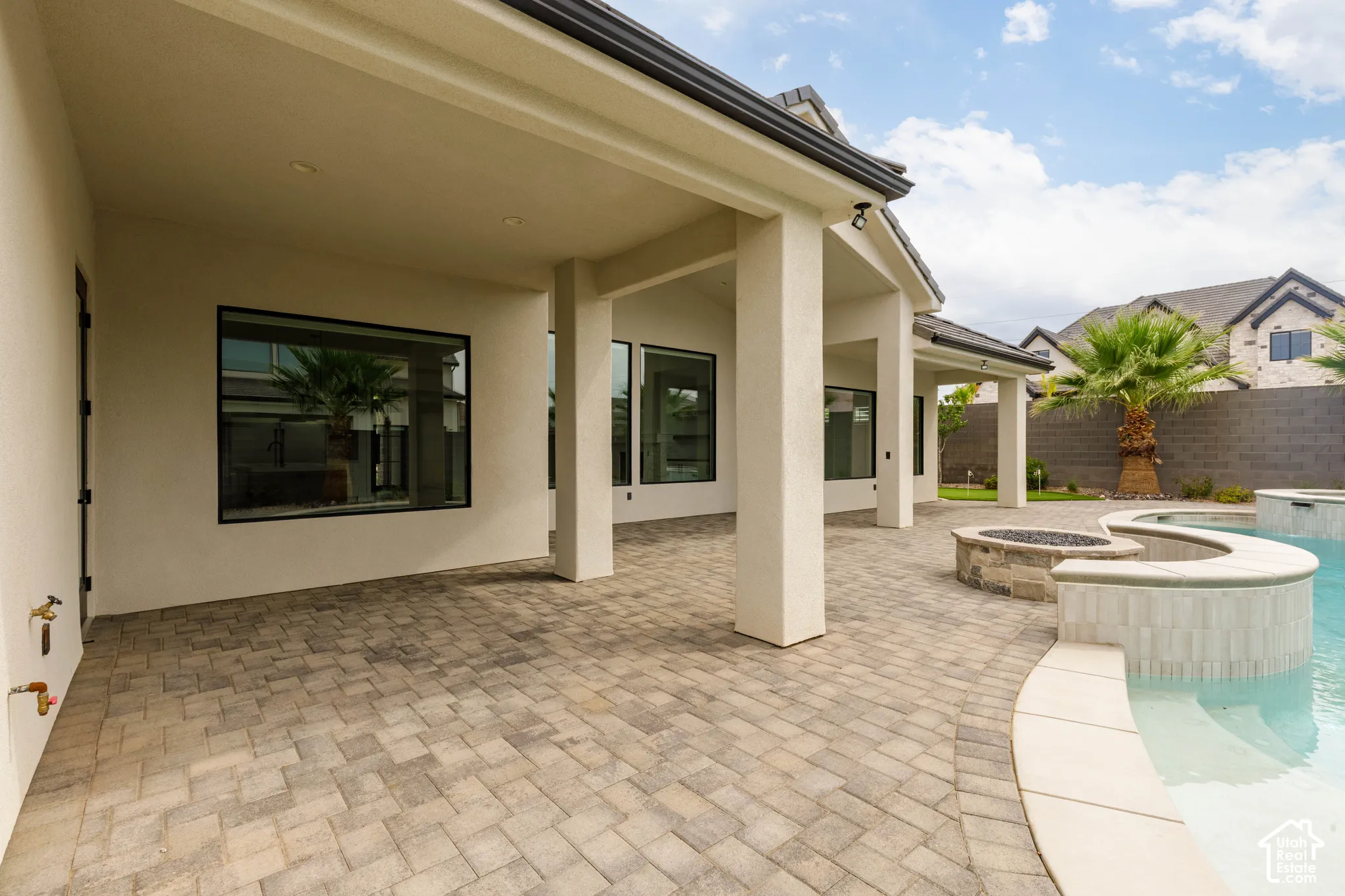 Covered patio with paver flooring, a built-in fire pit, and an integrated swimming pool with a raised spa
