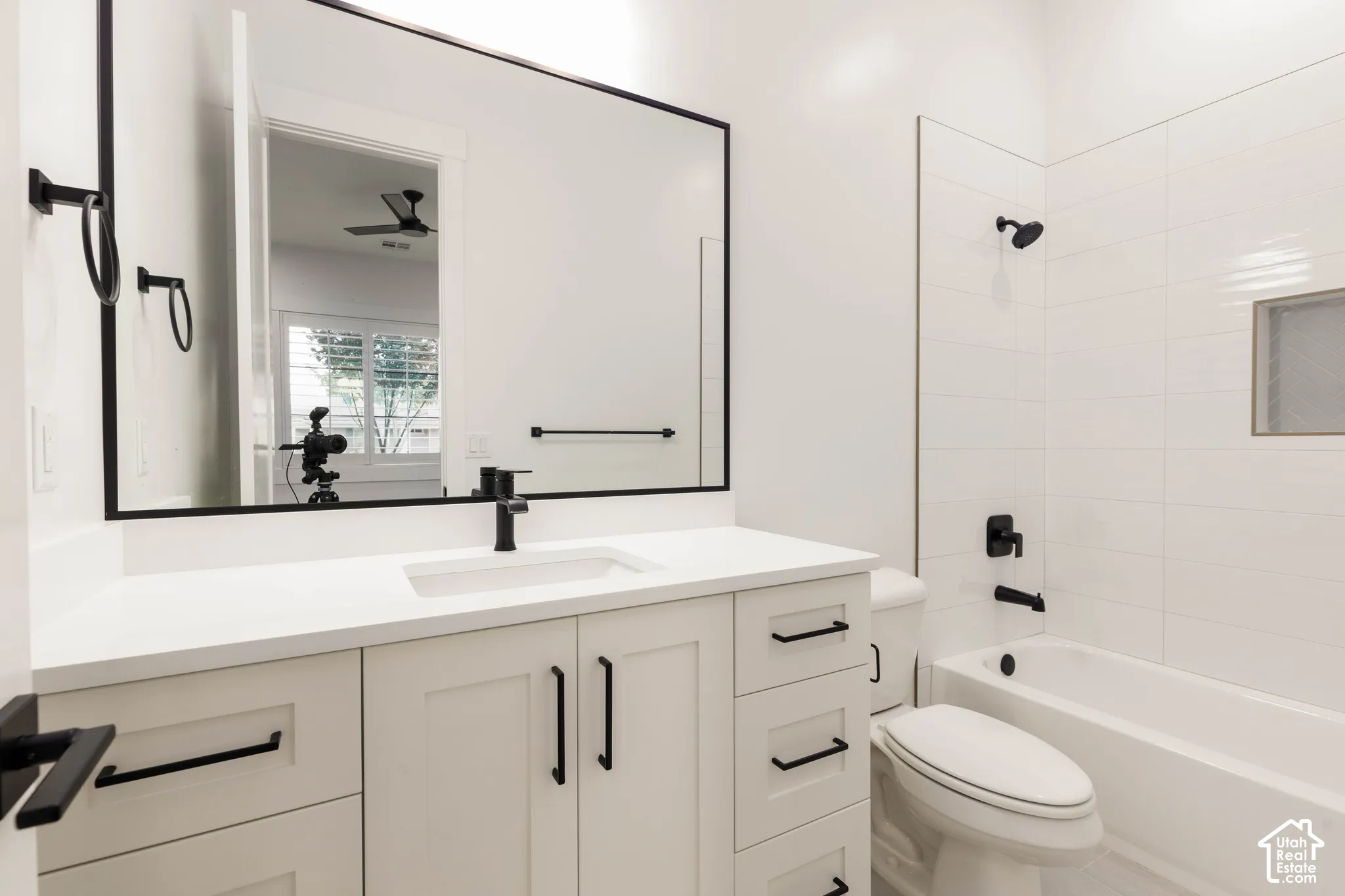 White vanity with shaker-style cabinetry, matte black hardware, integrated sink, and a large framed mirror
