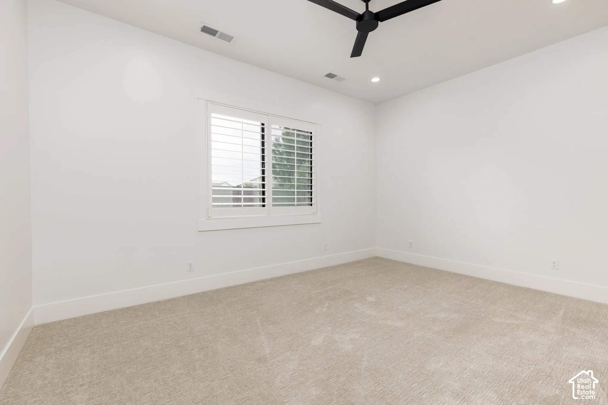 Recessed lighting, ceiling fan, white walls, plantation shutters, and carpeting