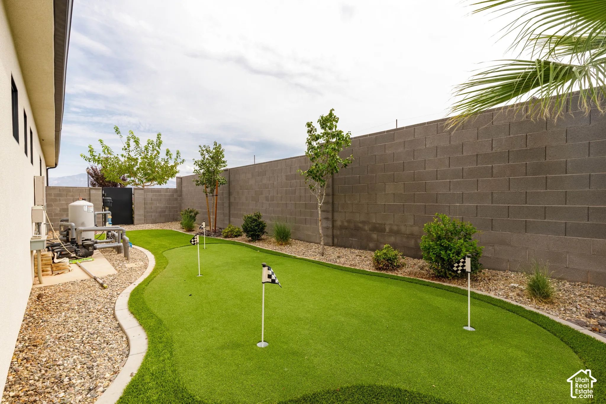 Private backyard featuring a putting green, decorative landscaping, and a block perimeter wall
