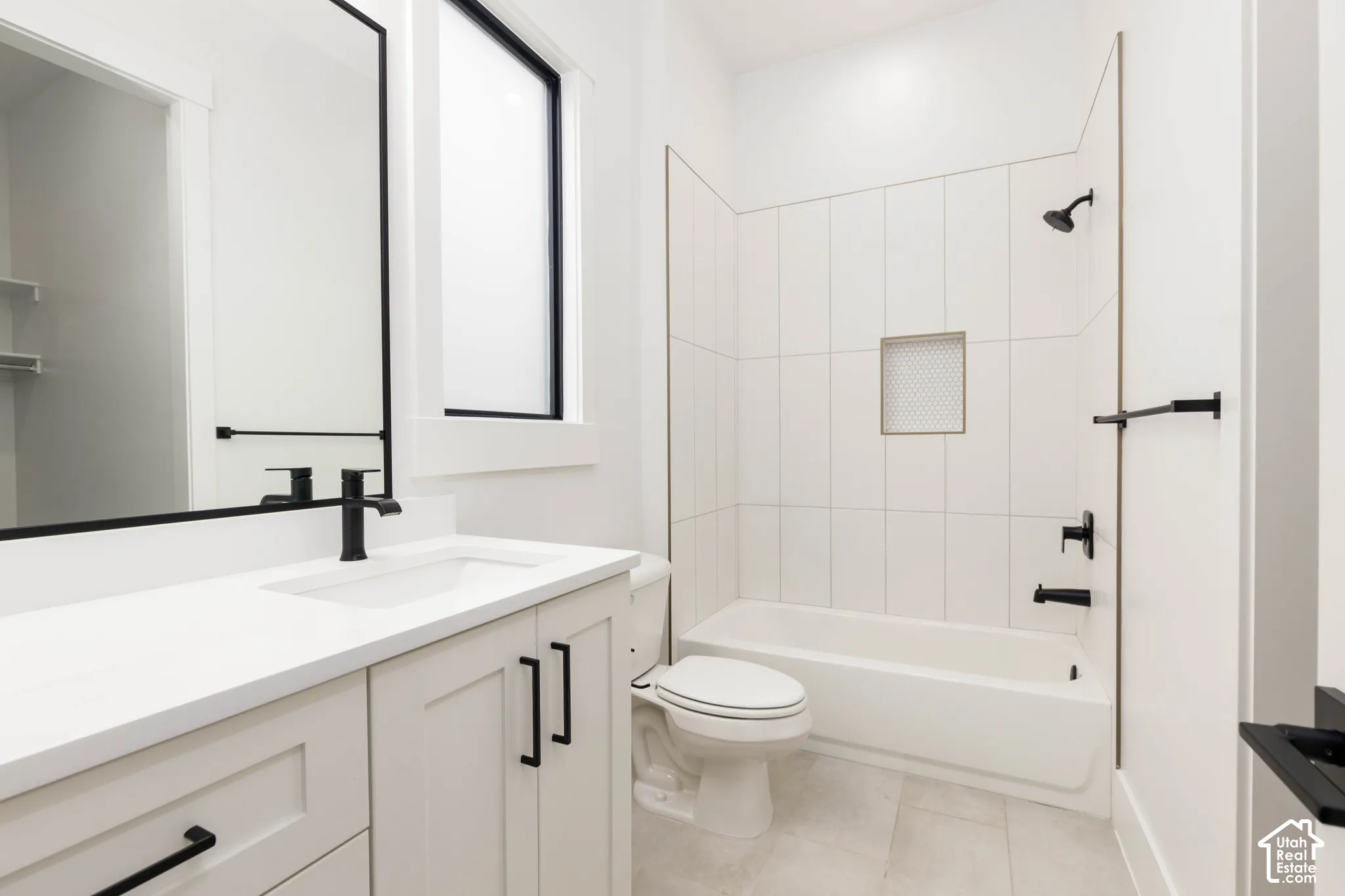 White vanity with shaker-style cabinetry, matte black hardware, and integrated sink