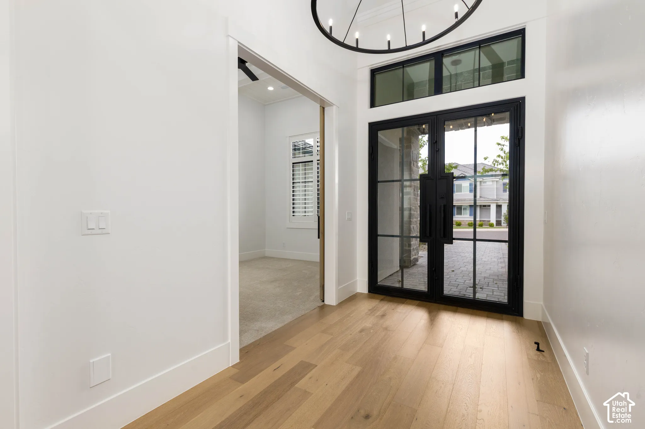 Double entry doors with black frames, transom windows, and wood-finish flooring