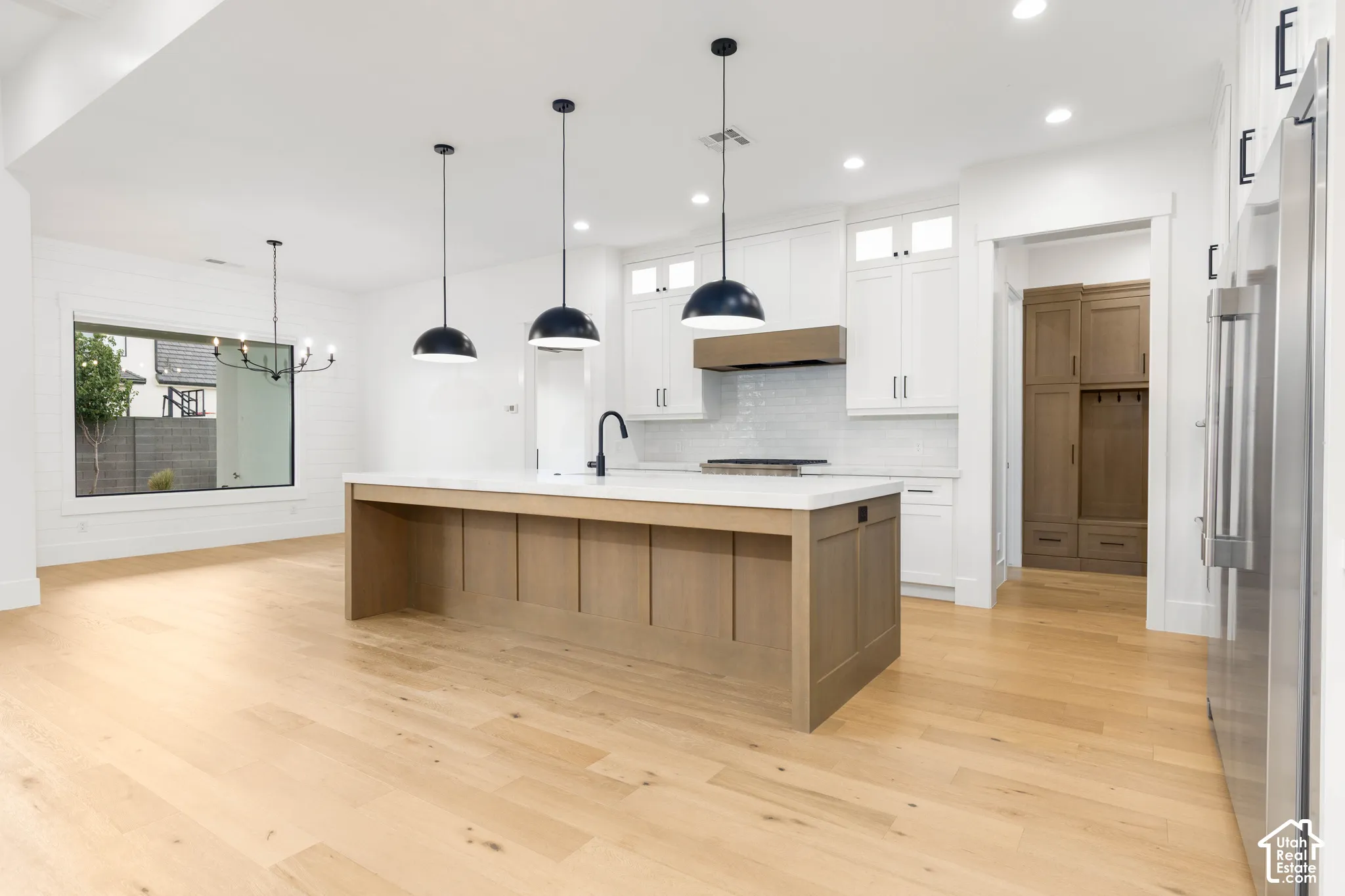 Open-concept kitchen with a light wood-finish island, white cabinetry, and recessed lighting