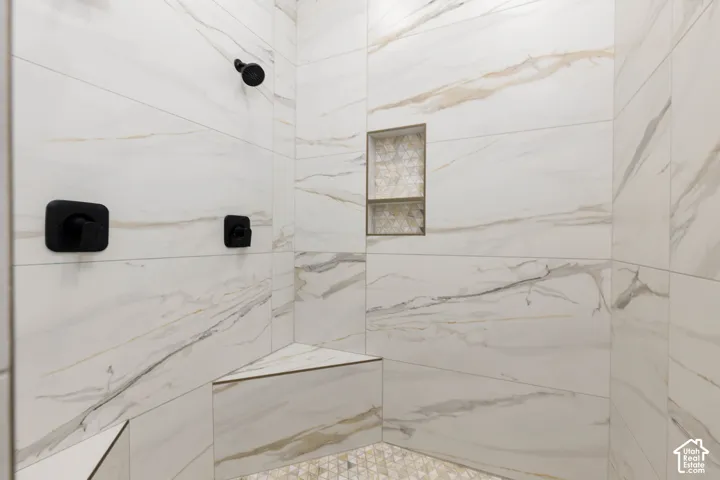 Tiled shower with a built-in bench, recessed niche with decorative tile, and matte black fixtures