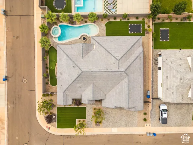 Curved swimming pool with an integrated spa, putting green, lush landscaping, and a tile roof