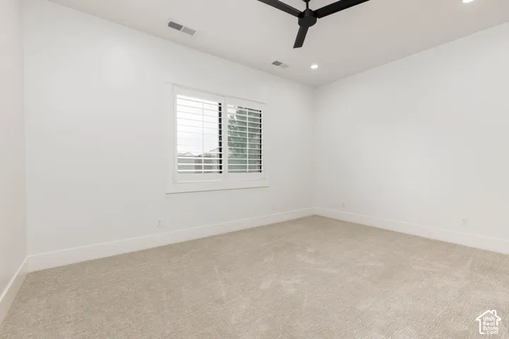 Recessed lighting, ceiling fan, white walls, plantation shutters, and carpeting