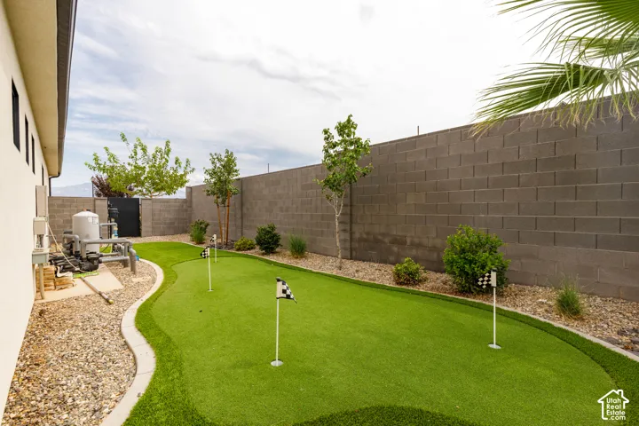 Private backyard featuring a putting green, decorative landscaping, and a block perimeter wall