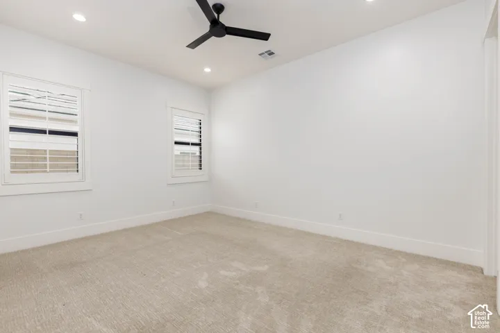 Recessed lighting, a ceiling fan, and carpeted flooring