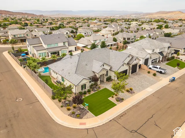 Contemporary residence with a multi-car garage, extensive paver driveway, and a private backyard featuring a pool and spa