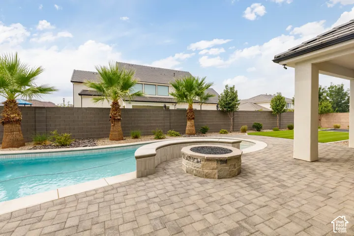 Paved patio with a built-in stone fire pit, adjacent to a pool with an integrated spa
