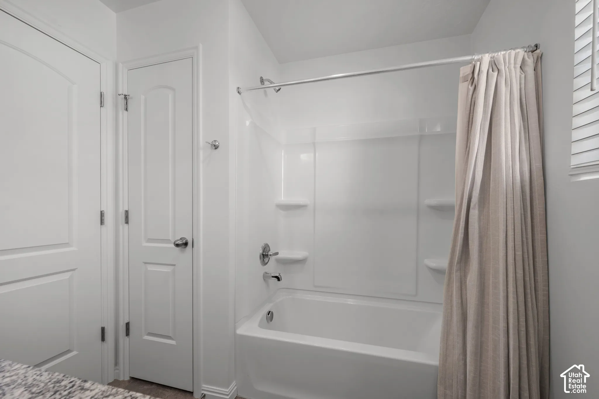 White tub and shower combination with integrated shelving, storage closet