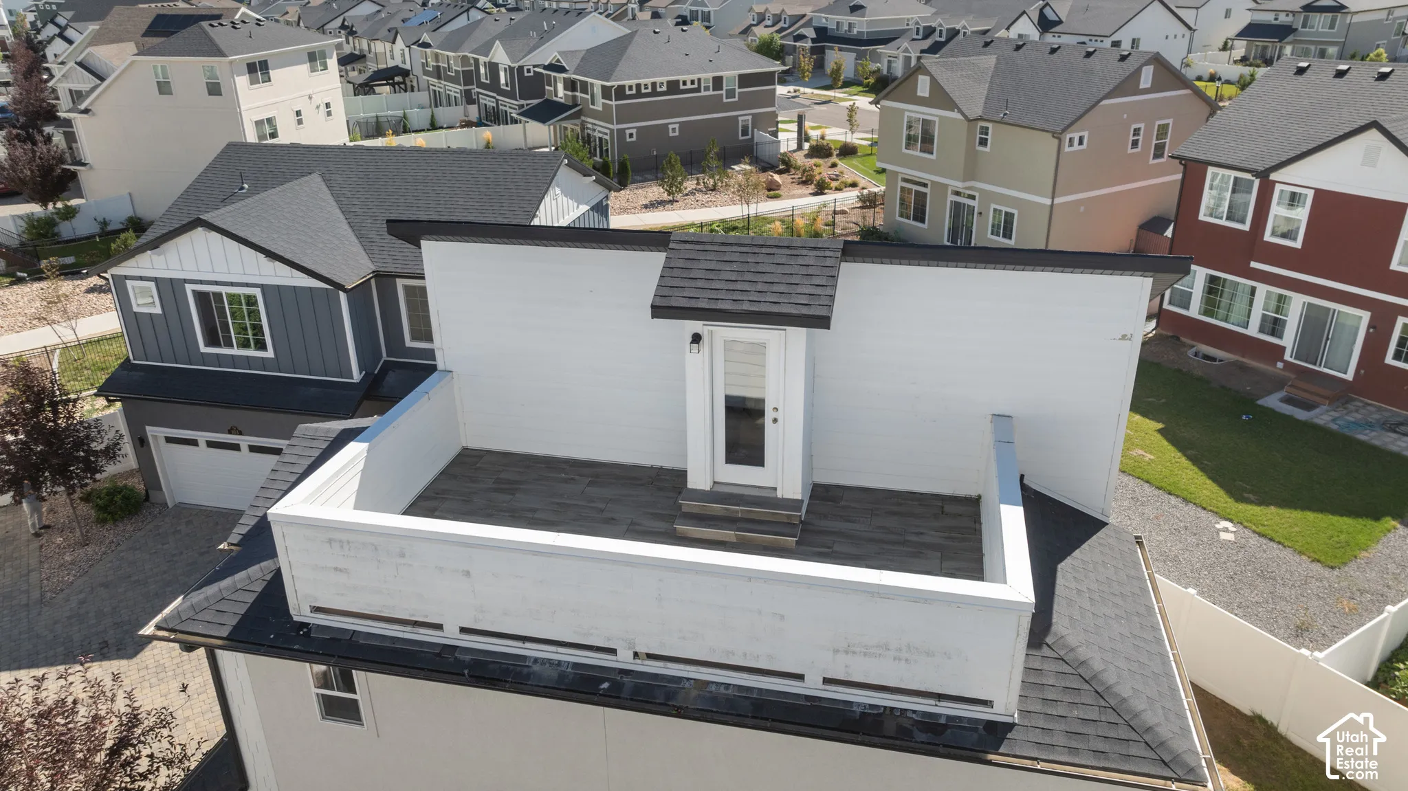 Rooftop deck featuring a privacy wall, exterior door, and dark-toned flooring