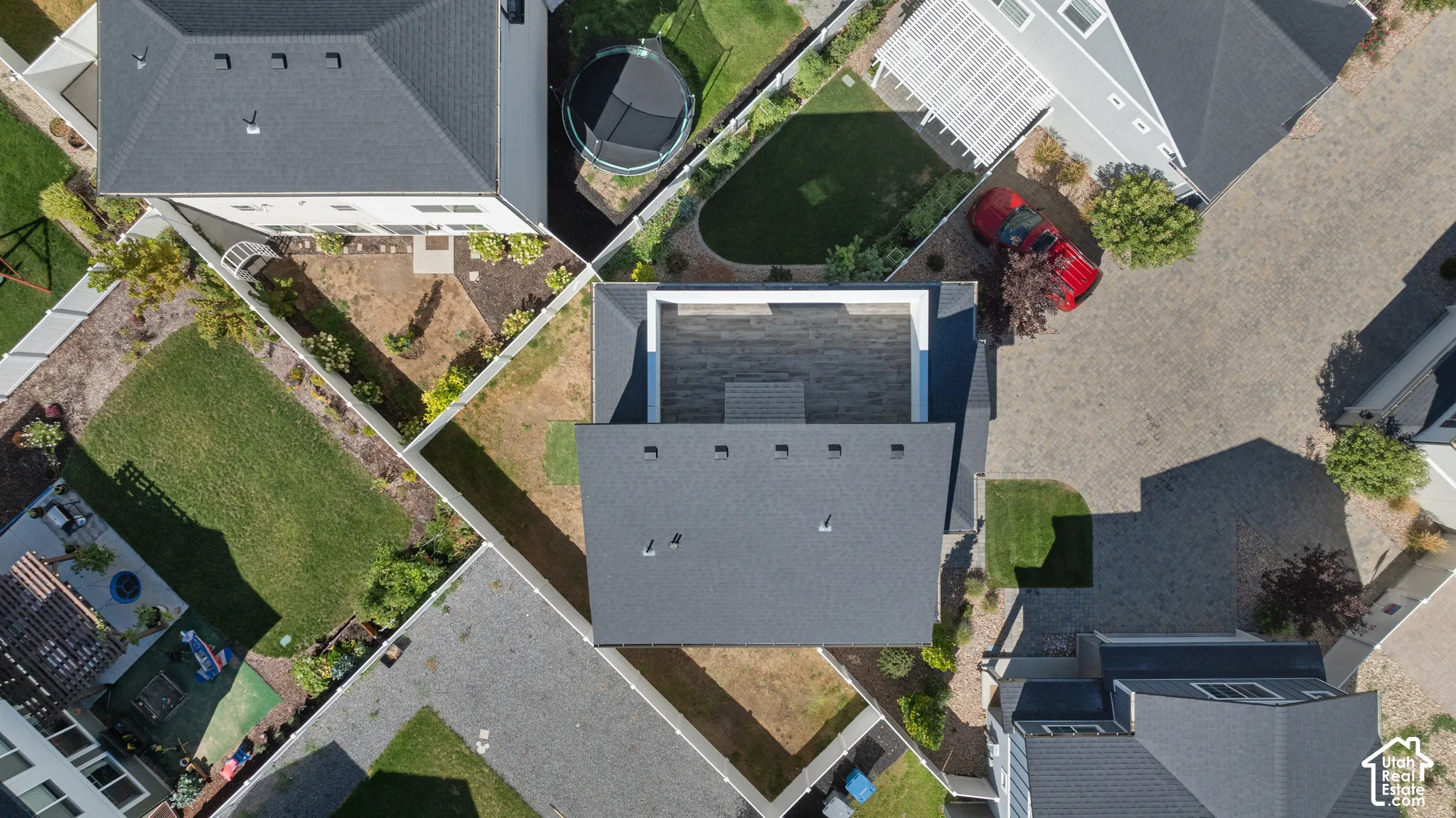 Gable roofline, flat roof section, fenced property lines, green space, and paved surfaces