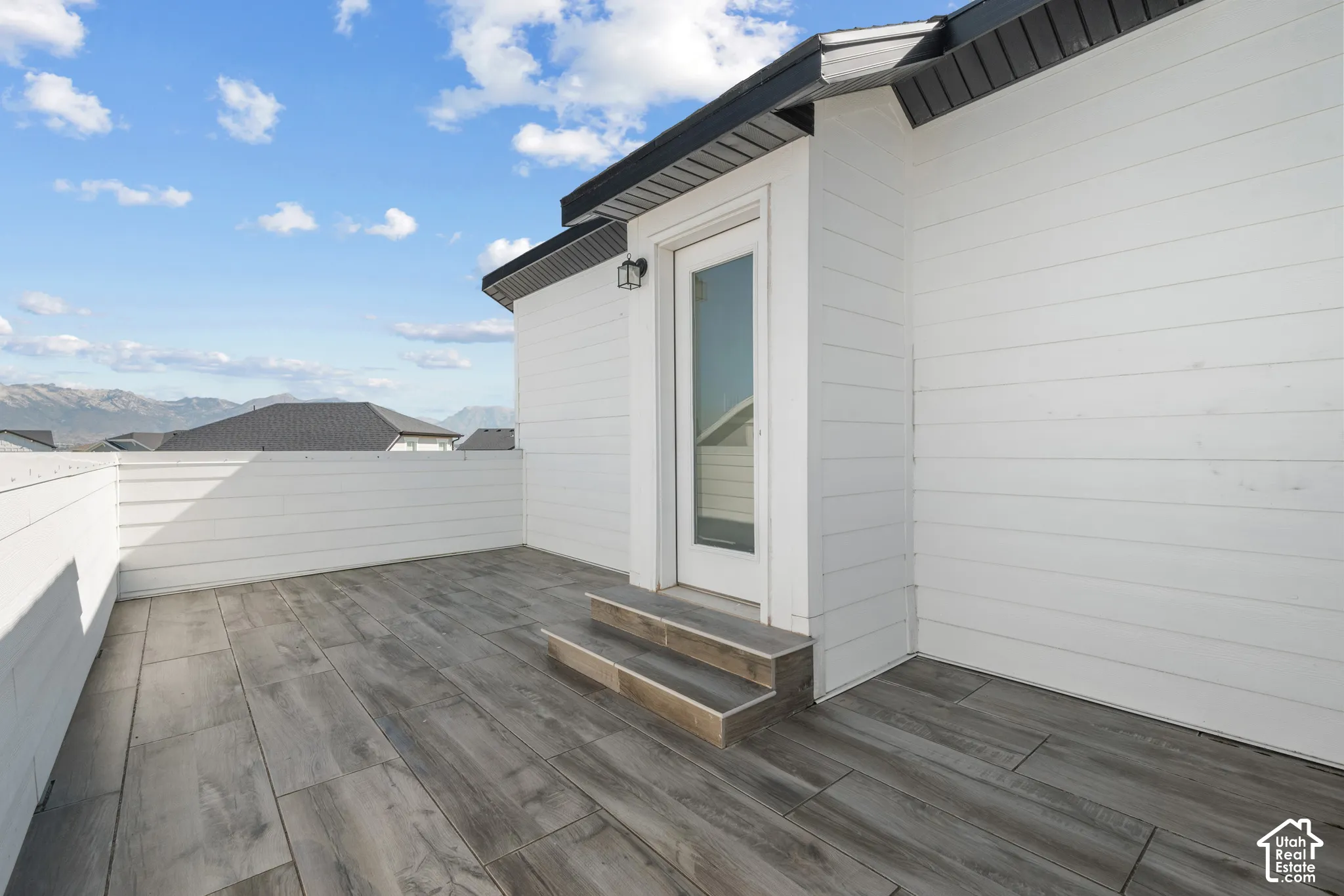 Outdoor patio with tile floor, white horizontal siding, and a white exterior door with glass insert