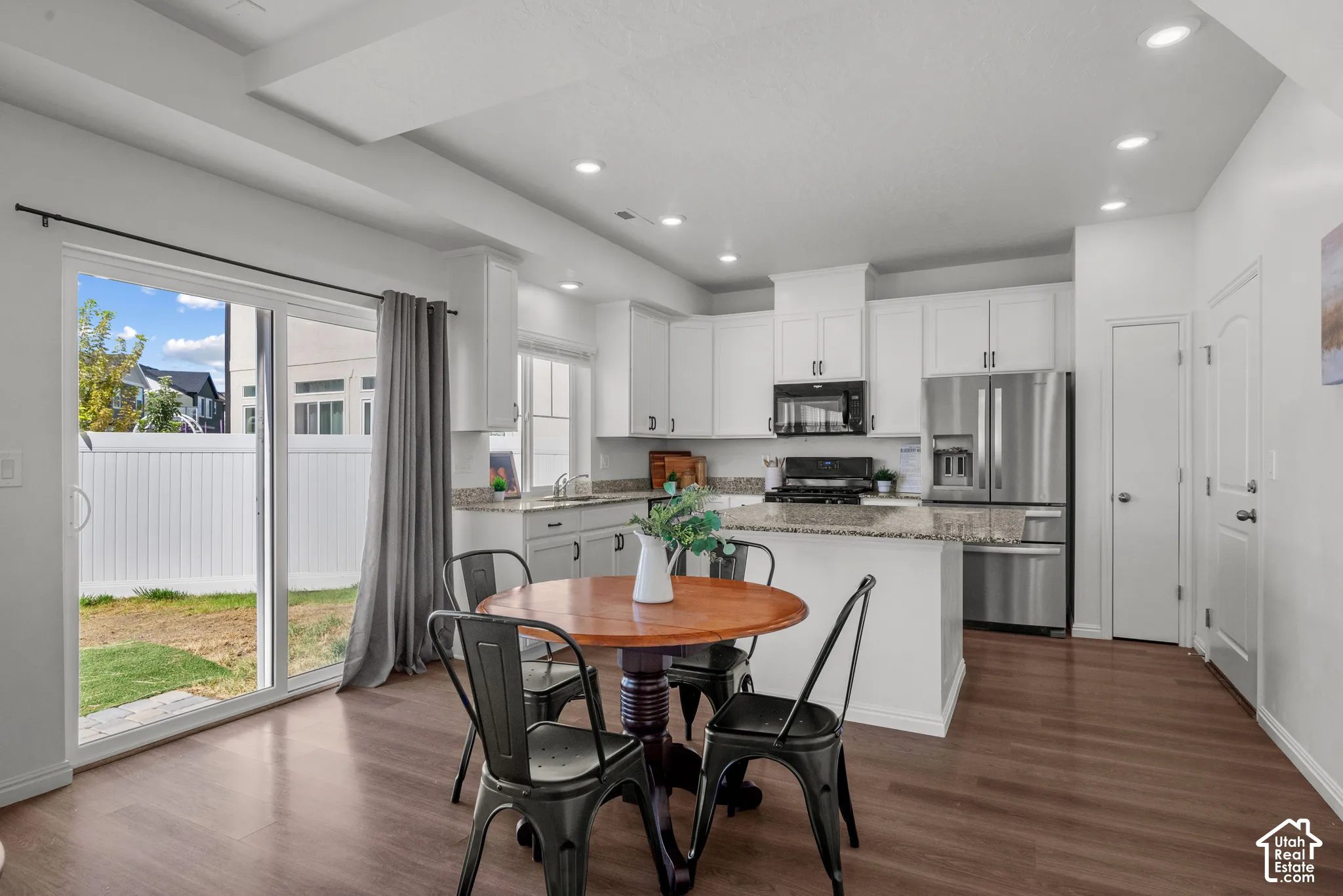 Kitchen featuring white cabinetry, granite countertops, stainless steel appliances, and wood-finish flooring