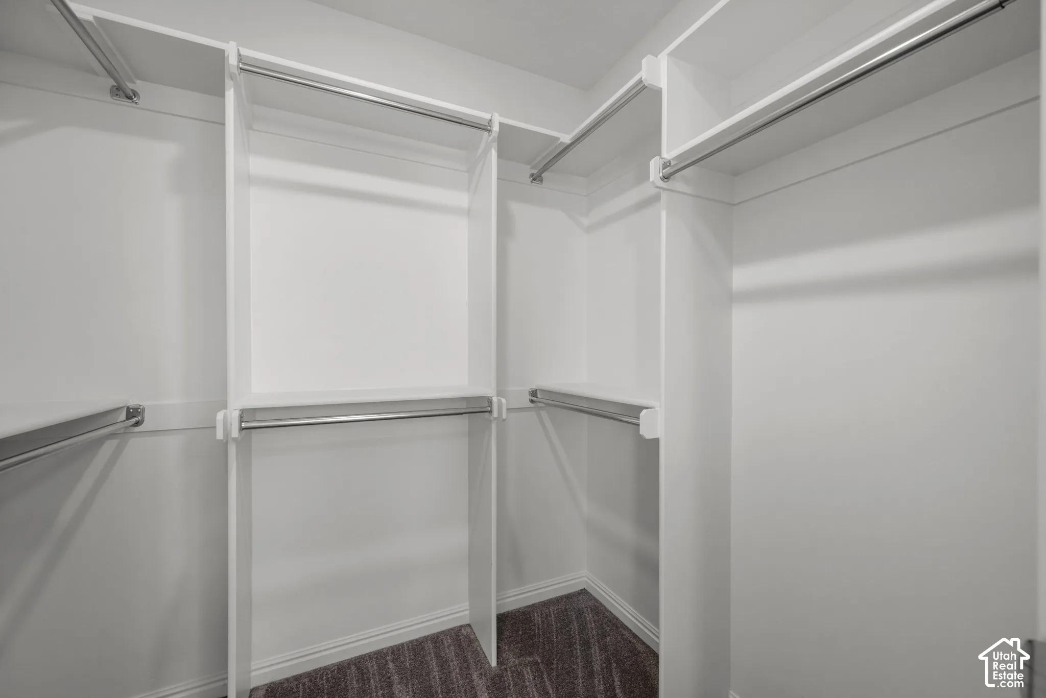 White custom closet system with multiple shelving tiers and chrome hanging rods, walk in closet