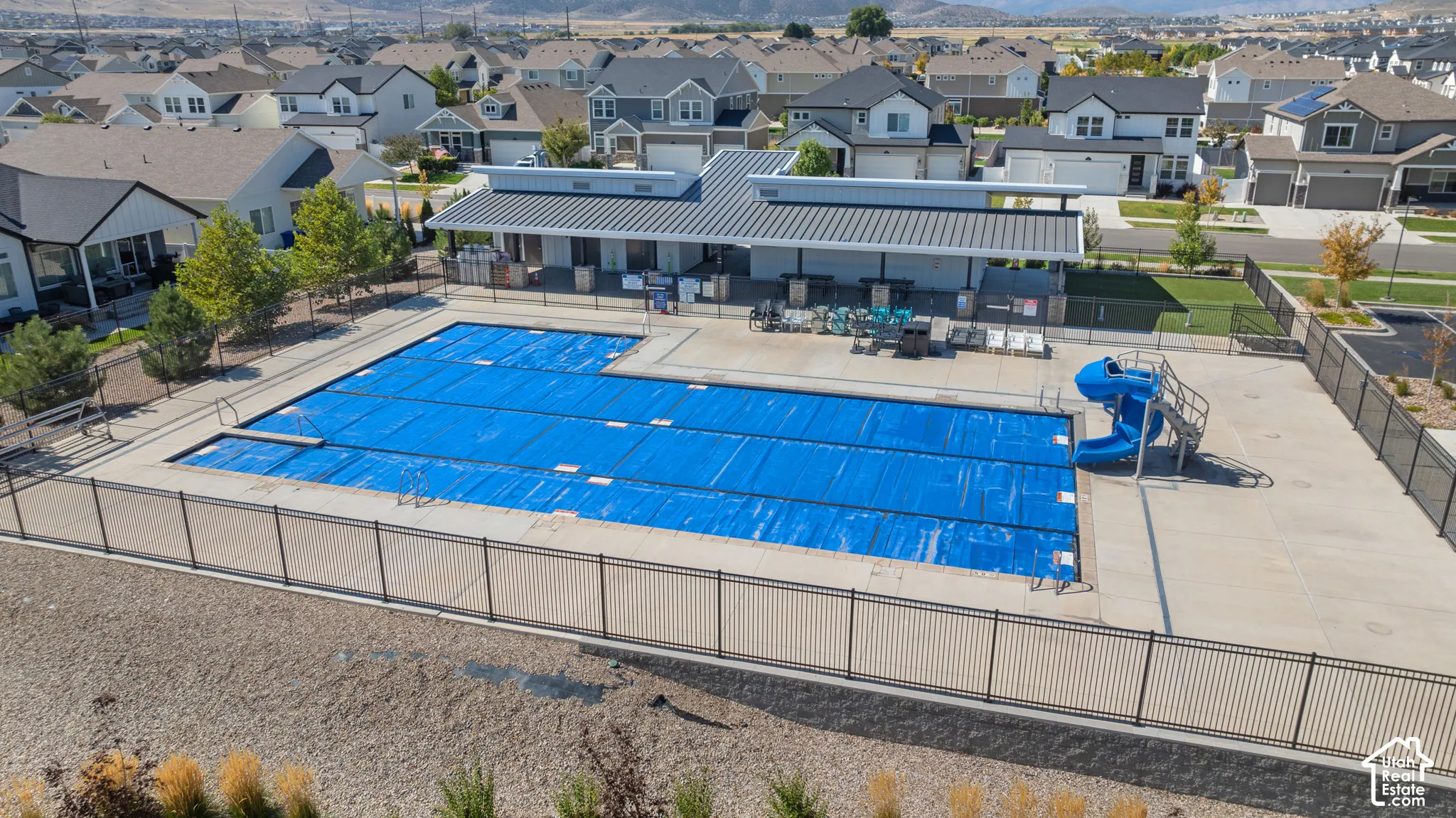 Community swimming pool with a diving board and waterslide, complemented by a covered lounge area and surrounding fencing