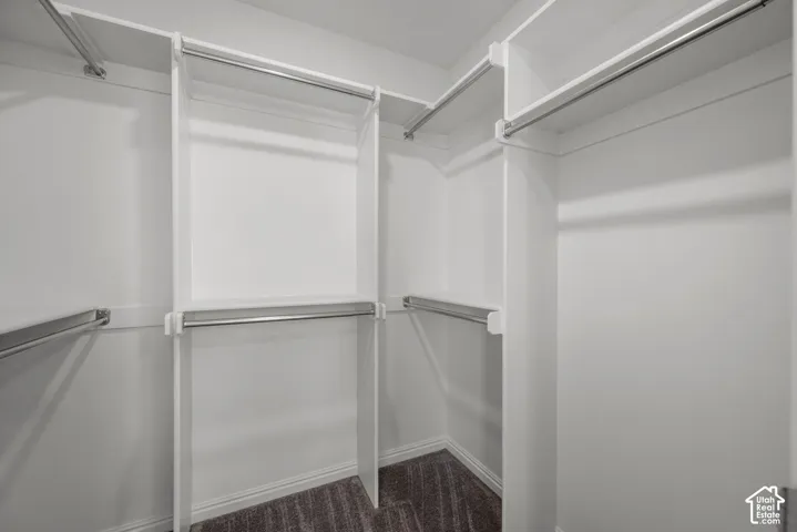 White custom closet system with multiple shelving tiers and chrome hanging rods, walk in closet