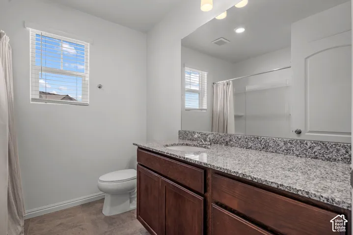Dark wood-finish vanity with an integrated sink, granite countertop, and chrome faucet, large countertop