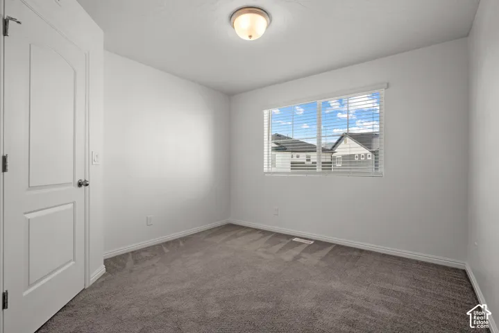 Light-filled room featuring neutral wall tones, gray carpeting, a window with wood blinds, and a flush mount ceiling light,
