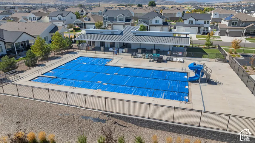 Community swimming pool with a diving board and waterslide, complemented by a covered lounge area and surrounding fencing