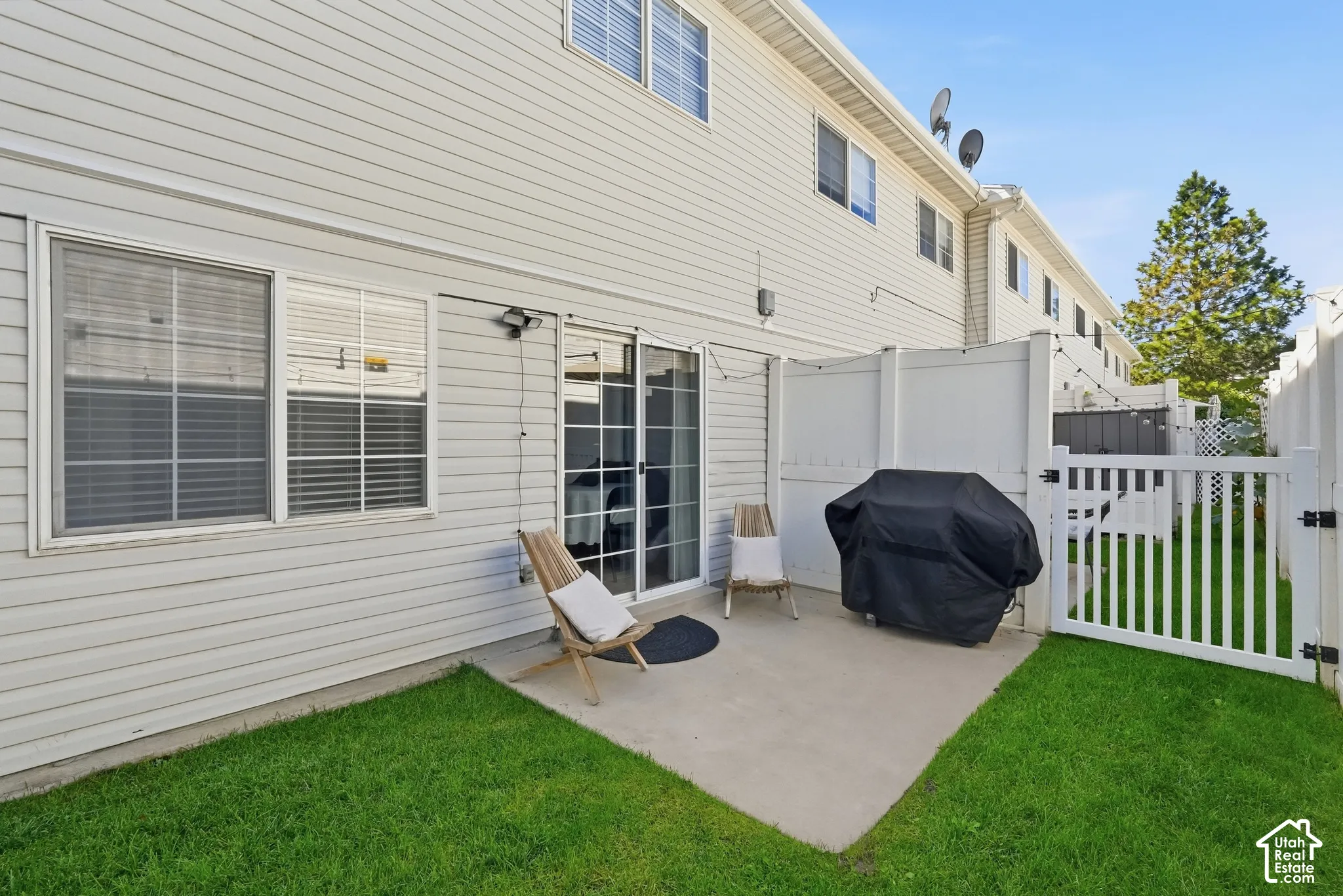 Private patio with concrete flooring, framed by white privacy fencing and a white picket gate