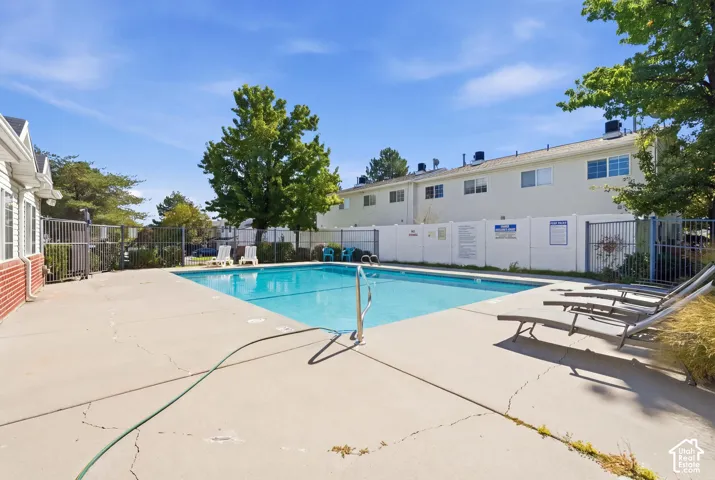 Outdoor swimming pool with concrete decking, surrounding perimeter fencing, and adjacent building structures