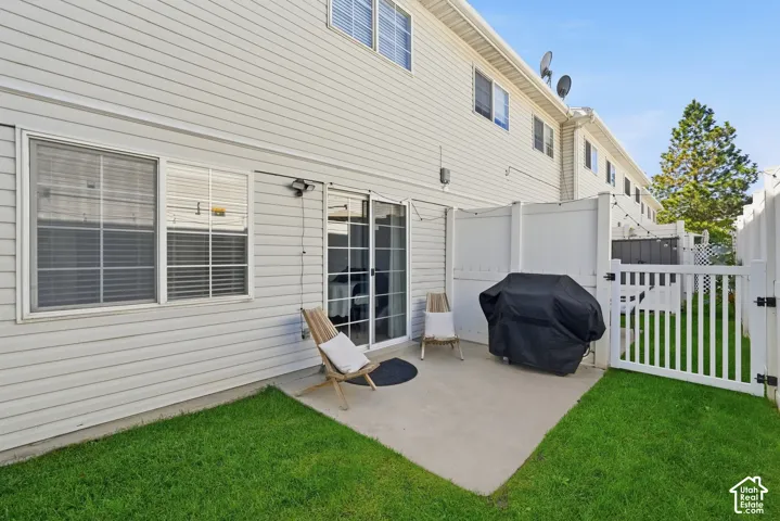 Private patio with concrete flooring, framed by white privacy fencing and a white picket gate