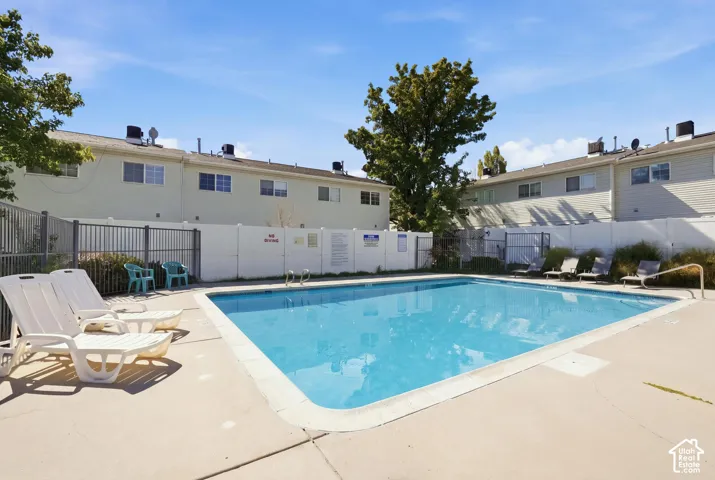 Outdoor swimming pool with concrete surround, perimeter fencing, and adjacent multi-story residential structures