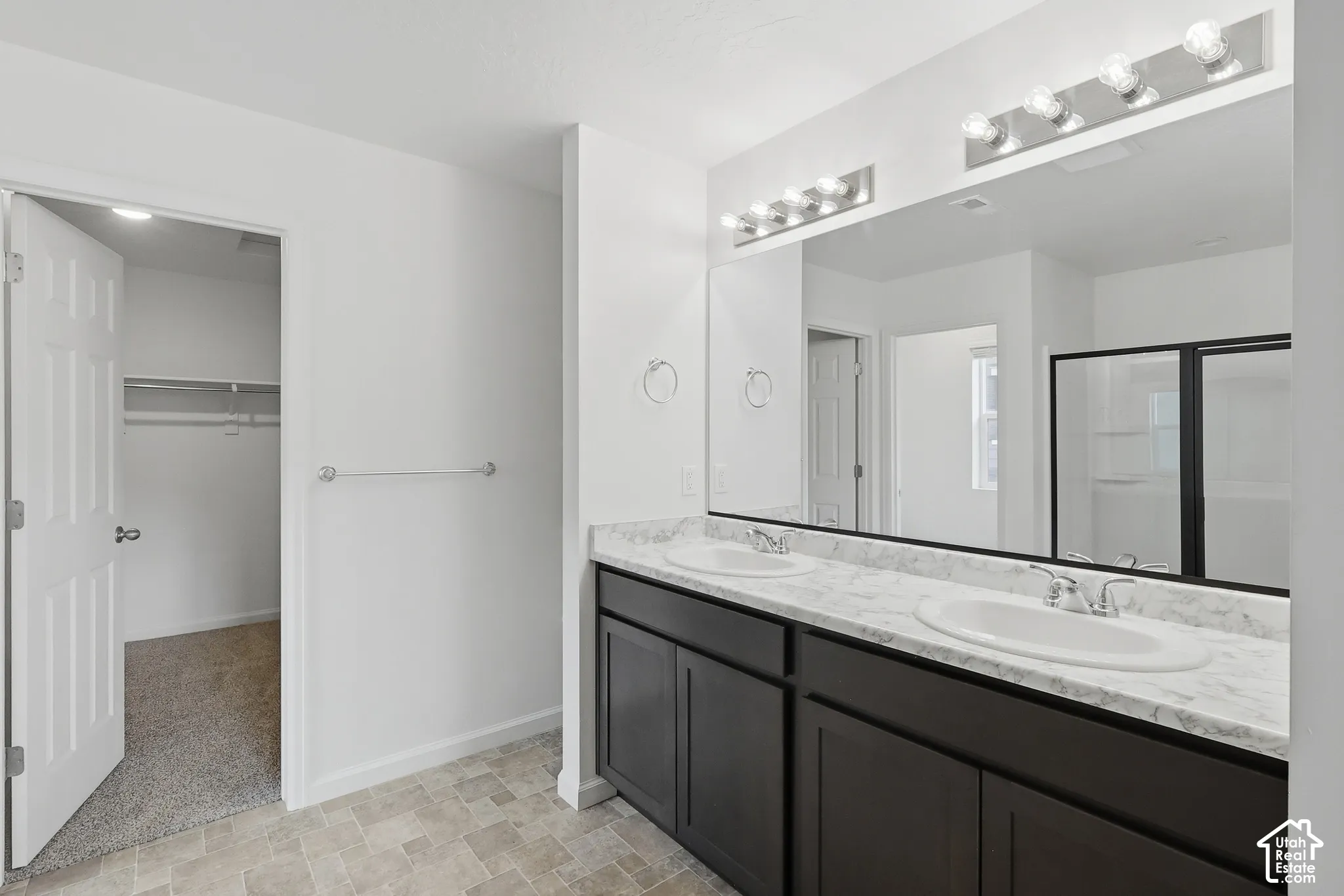 Dual vanity with undermount sinks, spacious mirror, and dark cabinetry
