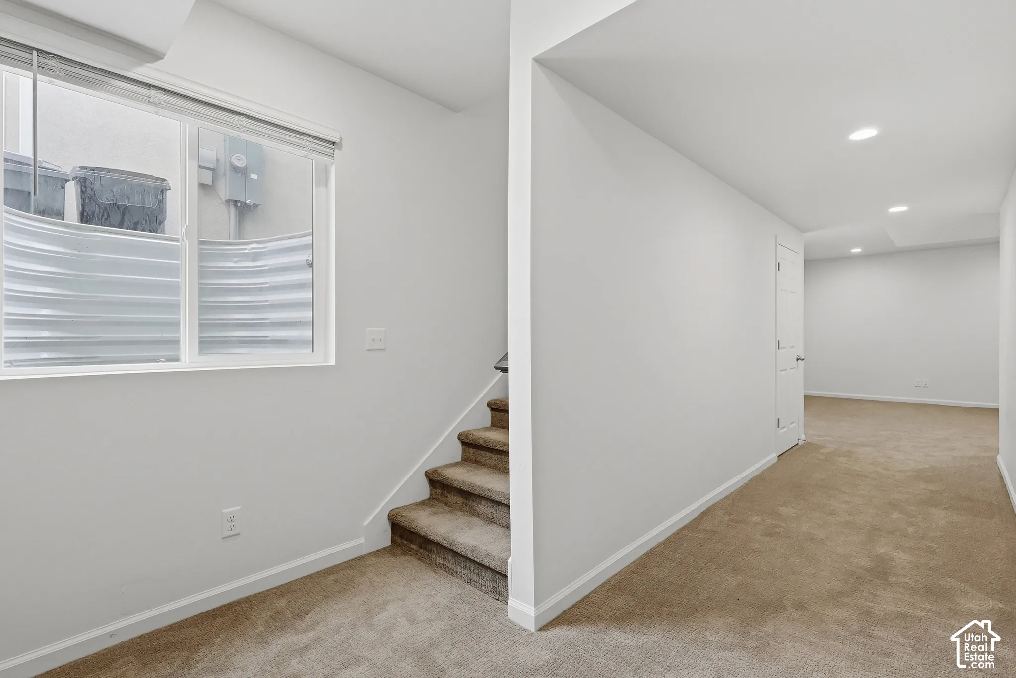 Carpeted stairs leading to a lower level with recessed lighting, carpeted flooring, and white walls