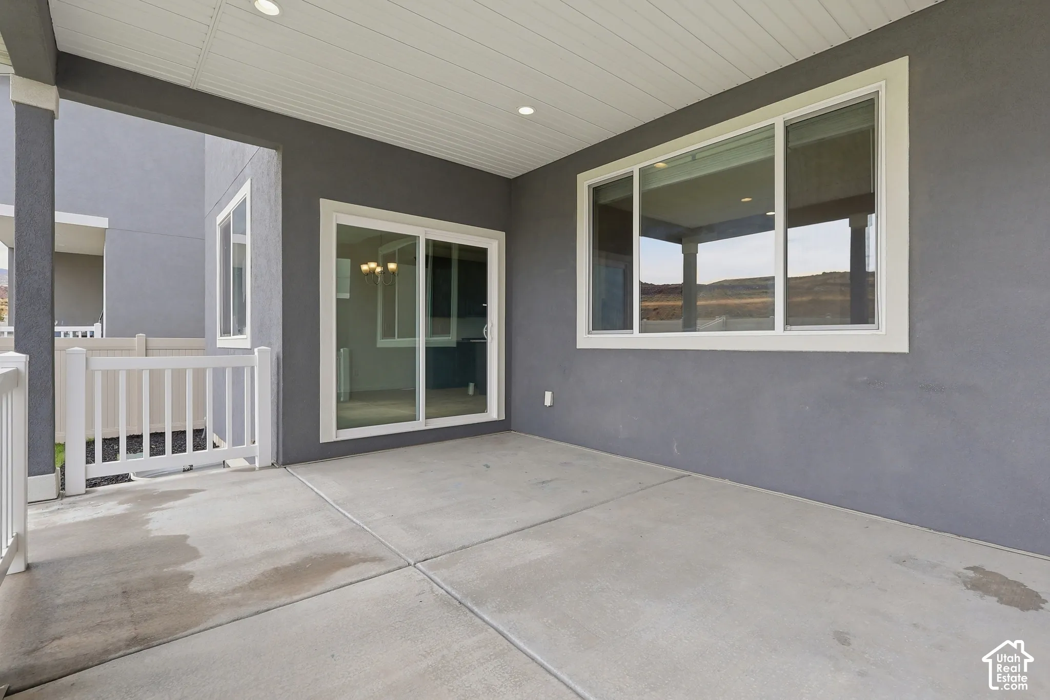 Covered concrete patio with white railing