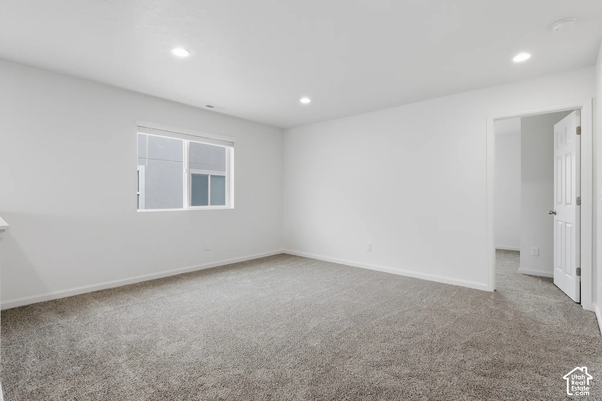 Recessed ceiling lighting, white interior walls, gray carpeting, white trim, and a window with blinds