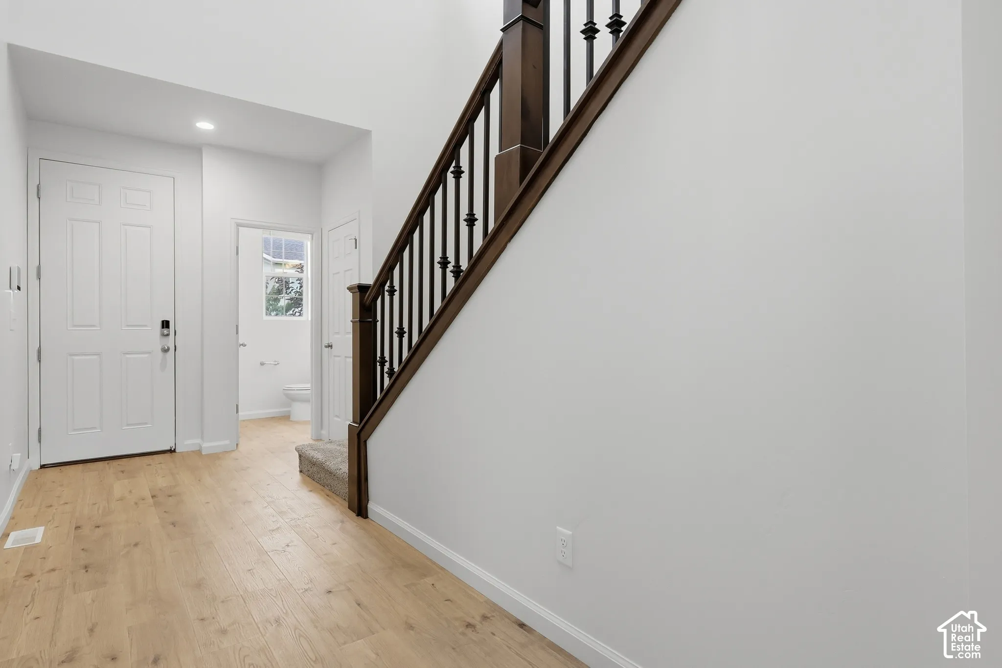 Wood-finish flooring, white paneled doors, recessed lighting, carpeted staircase, and dark wood handrail